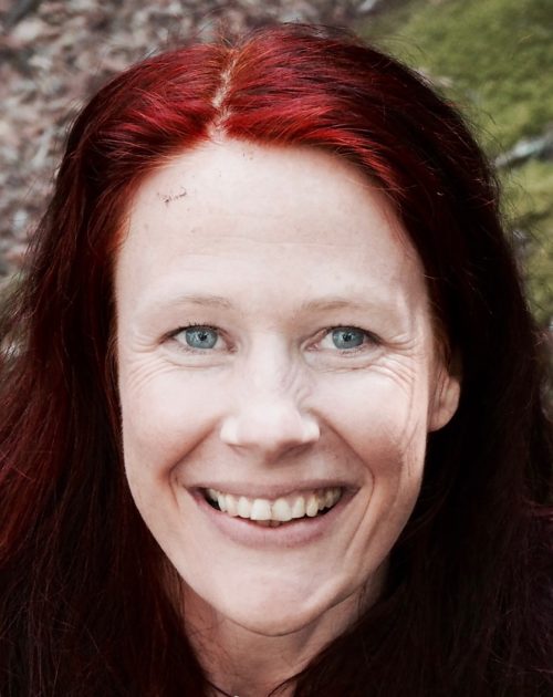 Photo of Petra Bongartz. Petra has red hair and blue eyes and is smiling at the camera.
