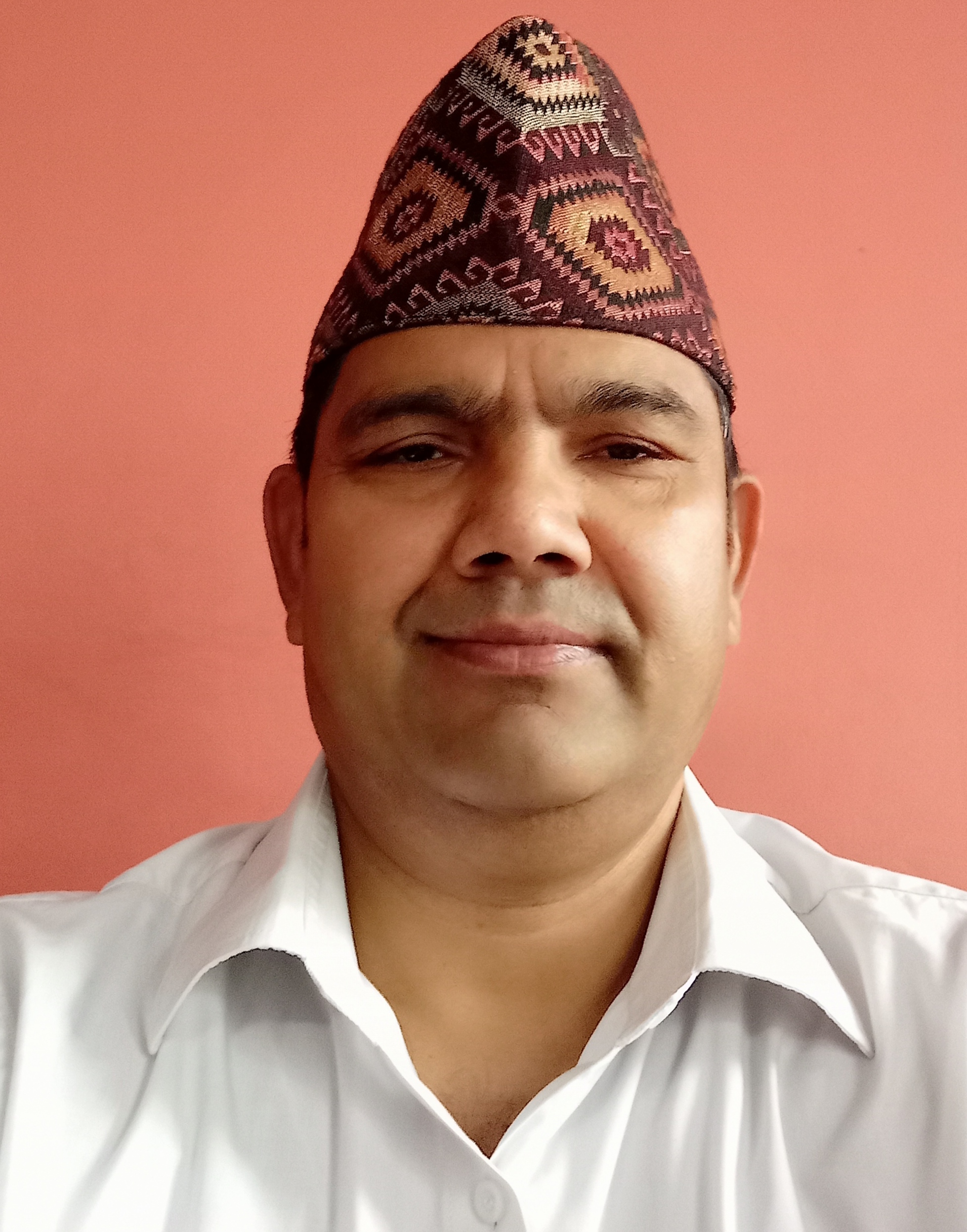 Photo of Kamal Adhikari smiling at the camera and wearing a hat.